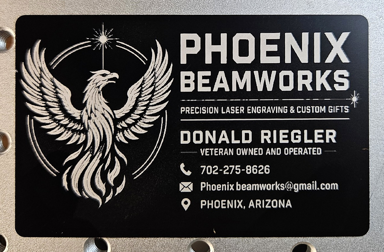 Front of a black aluminum Phoenix Beamworks business card with engraved phoenix and corrected contact information